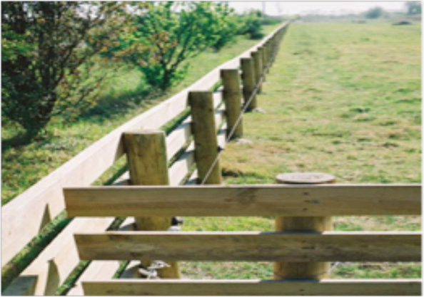 This picture shows a fenceline that continues out of focus down the length of a field.