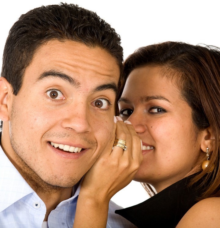 This picture shows a woman whispering into a man's ear.