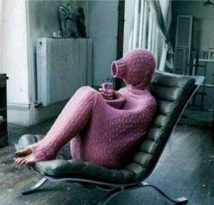 This picture shows a person sitting on a chair almost completely hidden inside a long sweater.