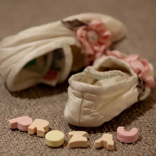 This picture shows baby shoes and the word "Prozac" spelled out with small, candy-like letters on the floor.