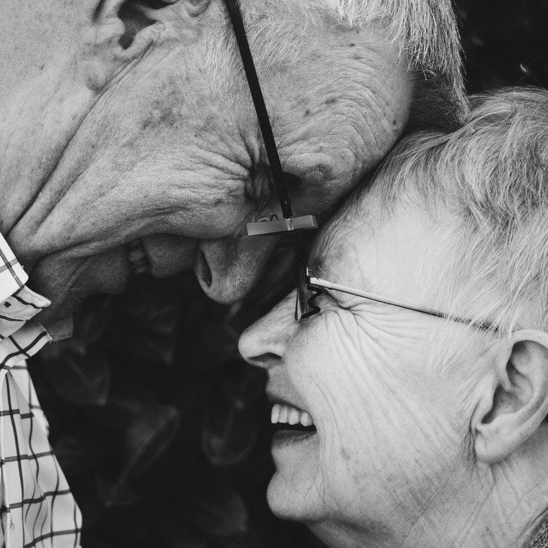 This picture shows a smiling elderly couple looking into each other's eyes while their foreheads touch.